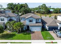 Two-story home with a brick driveway, lawn, and tropical landscaping featuring palm trees at 1268 Patterson Ter, Lake Mary, FL 32746