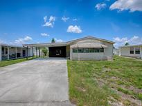 Well-maintained single-story home featuring an attached carport and manicured lawn at 1437 Apache Cir, Tavares, FL 32778