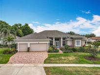Stunning single-story home with a three-car garage, manicured lawn, and vibrant landscaping at 1473 Lakemist Ln, Clermont, FL 34711
