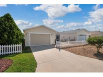 Charming single story home with light siding, an attached garage, and a white picket fence for curb appeal at 1622 Navidad St, The Villages, FL 32162
