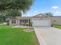 Charming single-story home with a well-manicured lawn, an attached two car garage and lovely landscaping at 17349 Se 76Th Flintlock Ter, The Villages, FL 32162