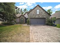 Charming stone-accented home featuring a paver driveway, manicured lawn, and attached two-car garage at 1893 Banning Beach Rd, Tavares, FL 32778