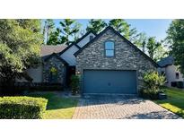 Charming exterior view of a stone-accented home with a paved driveway and well-manicured landscaping at 1893 Banning Beach Rd, Tavares, FL 32778