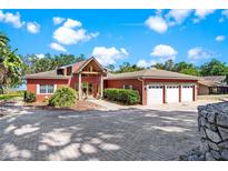 Lovely home featuring a charming red exterior, lush landscaping, and a large driveway at 2400 N Griffin Dr, Leesburg, FL 34748