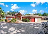 Charming one-story home featuring a circular driveway, three-car garage, and picturesque landscaping at 2400 N Griffin Dr, Leesburg, FL 34748