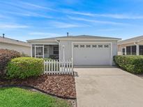 Charming single-story home featuring a white picket fence, and a two-car garage at 2450 Kingstree Pl, The Villages, FL 32162