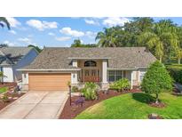 Charming home featuring a well-manicured lawn, lush landscaping, and a two-car garage, offering great curb appeal at 25129 Riverwalk Dr, Leesburg, FL 34748