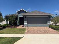 Charming single-story home featuring a brick driveway and lush landscaping at 709 Calabria Way, Howey In The Hills, FL 34737