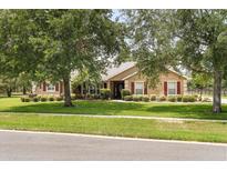 Charming single-story home with mature landscaping and red shutters at 7685 Lake Angelina Dr, Mount Dora, FL 32757