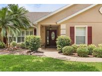 Charming home entrance featuring a beautifully landscaped yard and stylish front door with an oval glass window at 7685 Lake Angelina Dr, Mount Dora, FL 32757