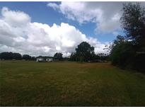 Expansive front yard with a dwelling amid verdant grass and mature trees under a cloudy sky at 7701 Groveland Farms Rd, Groveland, FL 34736