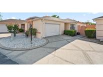 Beige single-Gathering home with a two-car garage, white rock landscape, and a concrete driveway in a sunny, pleasant neighborhood at 919 Medira Dr, The Villages, FL 32159