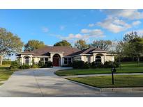 Charming one story home featuring a well-manicured lawn, mature trees, and a welcoming red front door at 987 Princeton Dr, Clermont, FL 34711