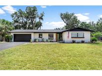 Charming single-story home with a well-manicured lawn and an attached garage at 1016 Cottonwood St, Leesburg, FL 34748