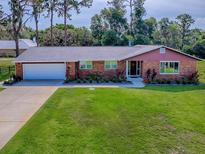 Charming brick home with a well-maintained lawn, lush landscaping, and a two-car garage at 111 Cardinal Ln, Eustis, FL 32726