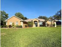 Well-maintained single-story home with a manicured lawn and mature landscaping at 11301 Via Mari Cae Ct, Clermont, FL 34711