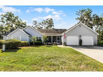 Charming single-story home with a well-manicured lawn and attached two-car garage, offering inviting curb appeal at 1350 Mosswood Dr, Leesburg, FL 34748