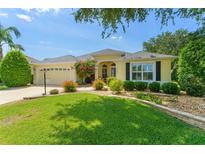 Charming yellow home with lush green lawn, lovely landscaping, and a two-car garage at 1446 Arbor Trl, The Villages, FL 32162