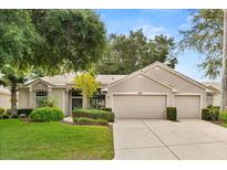 Charming single-story home featuring a well-manicured lawn, mature trees, and a spacious three-car garage at 2112 Saint Ives Ct, Clermont, FL 34711