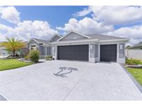 Spacious driveway featuring a palm tree insignia that leads to a charming single Gathering home with a three car garage at 2129 Landrea Loop, The Villages, FL 32163
