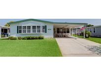 Charming single-story home with green trim, a well-manicured lawn, and a covered carport at 3026 Myakka River Rd, Tavares, FL 32778
