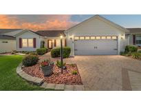 Charming single-story home featuring a paved driveway, manicured landscaping, and a two-car garage at 3041 Batally Ct, The Villages, FL 32162