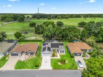 Beautiful aerial view of a home featuring well-maintained landscaping, solar panels, and a lovely green field in the background at 3534 Auburndale Ave, The Villages, FL 32162