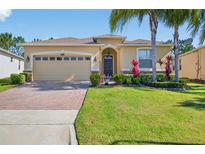 Charming single-story home with a brick driveway, lush lawn, and tropical landscaping at 3948 Serena Ln, Clermont, FL 34711