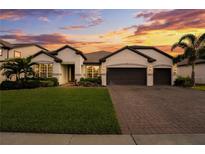 Beautiful home featuring a well-manicured lawn, brick driveway, and a two-car garage under a colorful, picturesque sunset at 743 Brooks Field Drive Dr, Winter Garden, FL 34787
