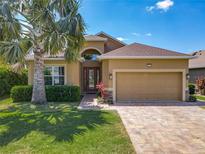 Charming single-story home with well-manicured lawn, mature landscaping, paver driveway, and attached two-car garage at 8387 Bridgeport Bay Cir, Mount Dora, FL 32757