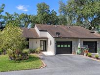 Charming exterior of the two-story townhome featuring attached garages and lush landscaping at 903 Belle Oak Dr, Leesburg, FL 34748
