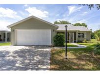 Charming single-story home with a well-maintained lawn, an attached garage, and a cozy screened-in porch at 923 Oleander St, The Villages, FL 32159