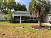 Charming single-story home featuring a well-maintained lawn and a mature palm tree at 1030 Vermont Ave, Lady Lake, FL 32159