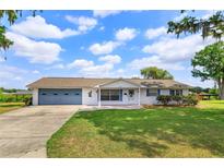 Charming single-story home with a lush green lawn, blue shutters and a matching blue garage door at 1110 Fairfax St, Leesburg, FL 34748