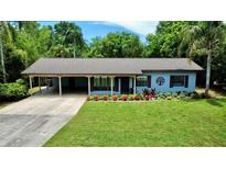 Charming single-story home with a well-manicured lawn and colorful flower bed at 11114 Lake Eustis Dr, Leesburg, FL 34788