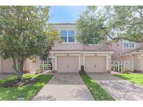 A charming, light pink two-story townhome with attached garage, and a well-manicured front lawn at 1288 Grady Ln, Davenport, FL 33896
