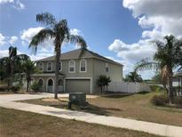 Two-story home featuring arched windows, a two-car garage, and lush palm trees enhancing its curb appeal at 1730 Ridgemoor Dr, Mascotte, FL 34753