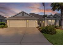 Charming single-story home featuring a three-car garage, well-manicured lawn, and mature palm trees at 2124 Hames Ln, The Villages, FL 32162