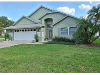 Charming single-story home featuring a lush front lawn, manicured landscaping, and an attached two-car garage at 2750 Coral Reef Way, Tavares, FL 32778