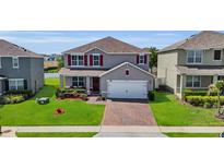 Charming two-story home with a brick driveway, well-manicured lawn and mature landscaping at 3441 Landing Vw, Tavares, FL 32778