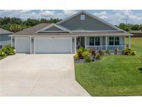 Charming home featuring a well-manicured lawn and a convenient two-car garage at 3532 Thorne Path, Oxford, FL 34484