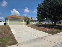 Well-maintained one-story home with a long driveway and a two-car garage, surrounded by mature trees at 8025 Cardinal Winds Ln, Mascotte, FL 34753