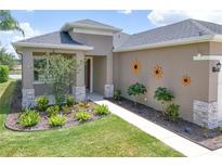 Charming home exterior with a well-manicured lawn, stone accents, and decorative floral accents at 8664 Bridgeport Bay Cir, Mount Dora, FL 32757