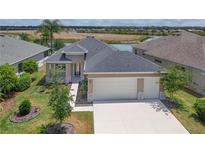 Inviting exterior of a home boasting a 2-car garage, a well-maintained lawn, and picturesque landscaping at 8664 Bridgeport Bay Cir, Mount Dora, FL 32757