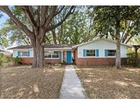 Charming single story home with brick facade, bright blue shutters, and mature trees in the front yard at 9752 County Road 121, Wildwood, FL 34785