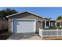 Home with a two-car garage and a white picket fence at 1070 Pinewood Pl, The Villages, FL 32162