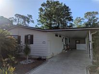 Charming home features a covered carport, a manicured garden, and a clean exterior design at 2871 Myakka River Rd, Tavares, FL 32778