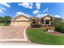 Inviting single-story home featuring a well-manicured lawn and a brick-paved driveway leading to a two-car garage at 3319 Barrington Ct, The Villages, FL 32162