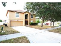 Two-story home with a two-car garage, large front lawn, and mature trees at 3329 White Blossom Ln, Clermont, FL 34711