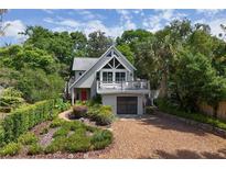 Inviting home exterior with a red front door, mature landscaping, and ample parking in a gravel driveway at 421 W 10Th Ave, Mount Dora, FL 32757